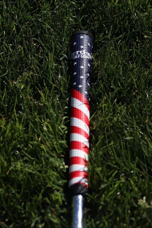 Golf club head with red and white striped design on grass