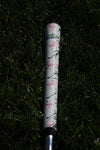 Golf club with a floral patterned grip on grass