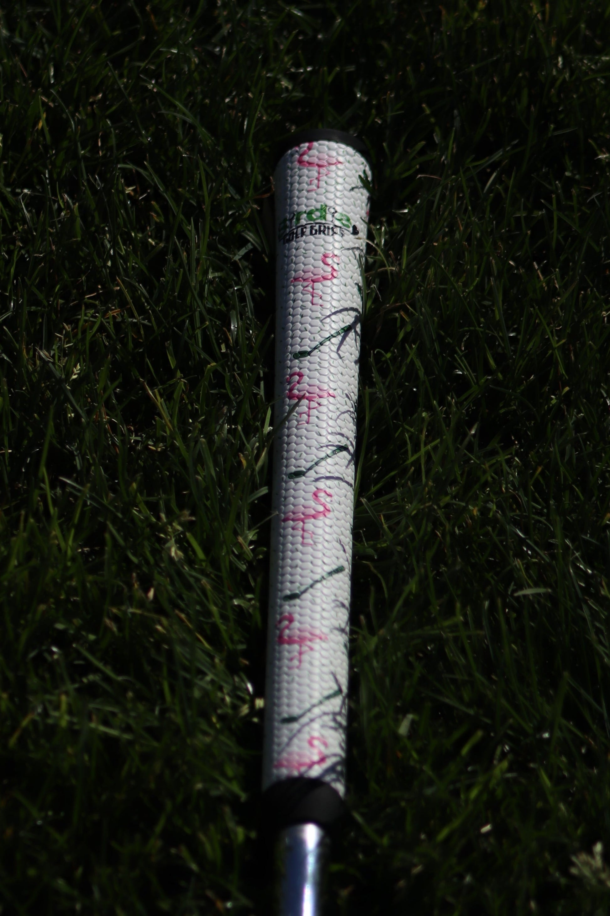 Golf club with a floral patterned grip on grass