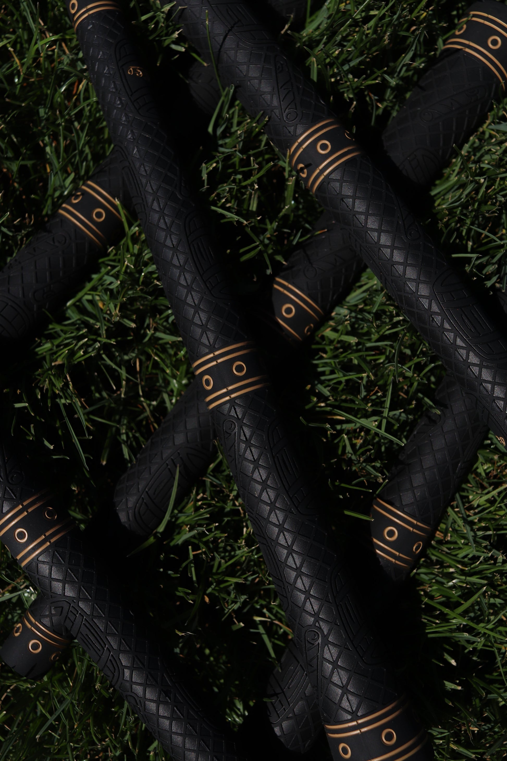 Birdie Golf Grips Smoke & Barrel black golf club grips with raised diamond texture and gold detailing on green grass.