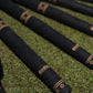 Birdie Golf Grips Smoke & Barrel black golf club grips with raised texture and gold detailing on a green grass field.